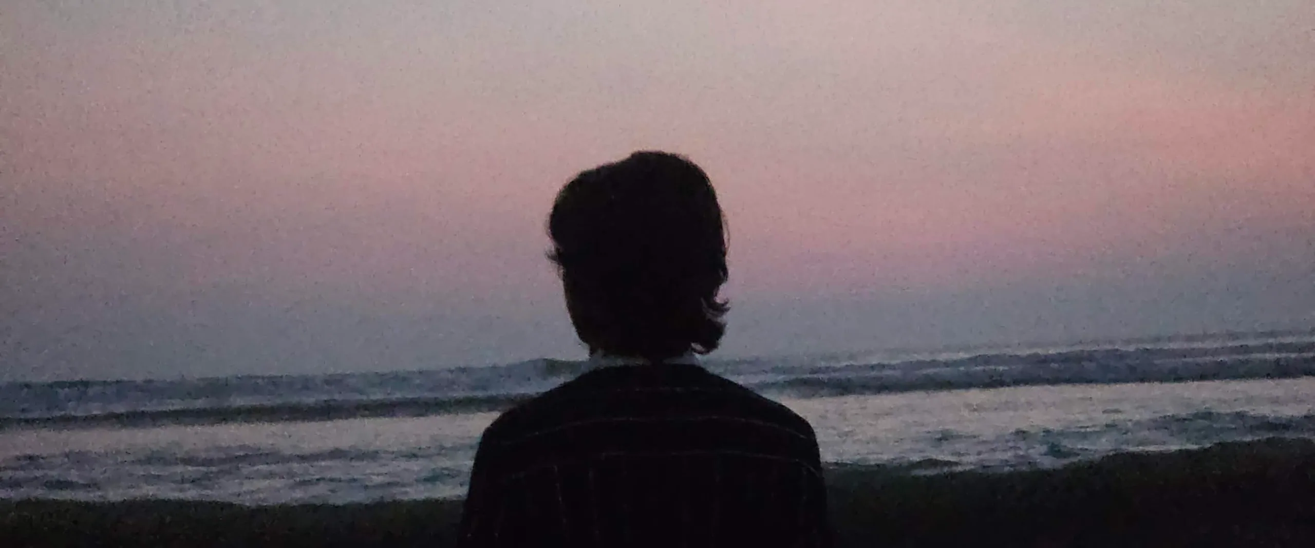 Portrait from behind, looking out over the sea at sunset