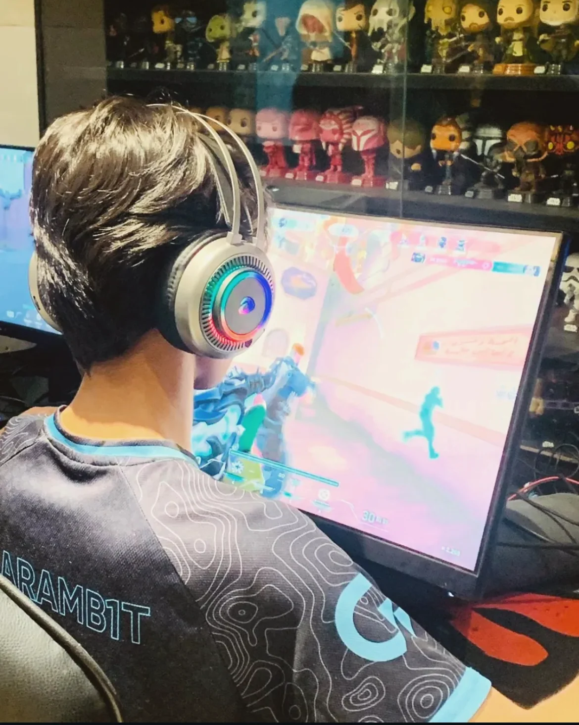 Gaming at a PC setup wearing a headset and a team jersey